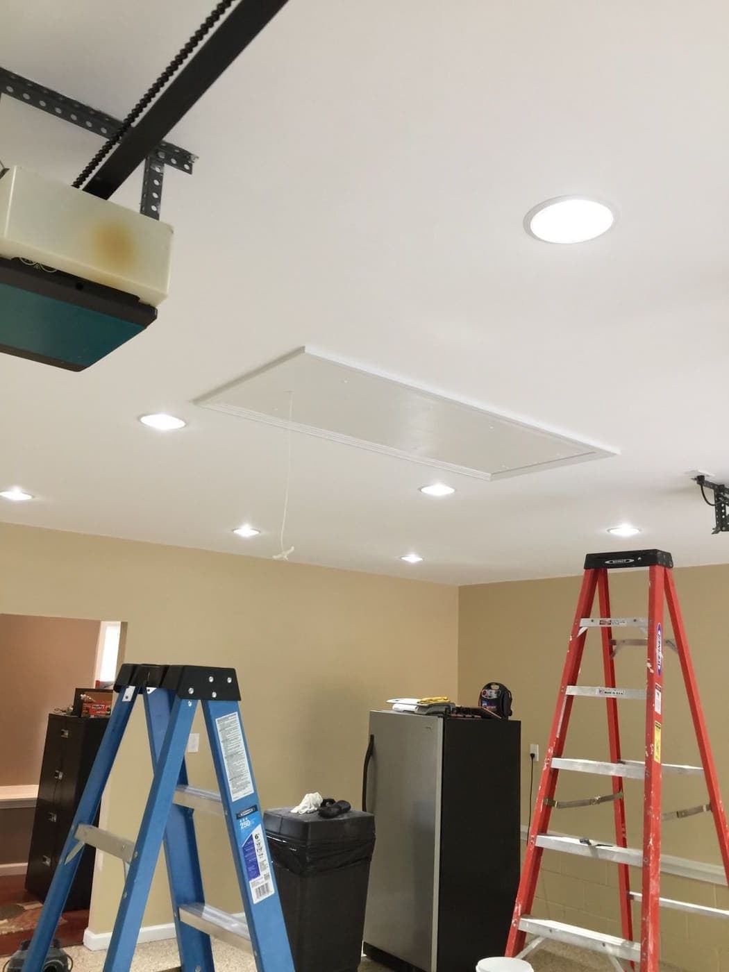 Inside Outside job site with a newly finished white ceiling, recessed lights and work ladders